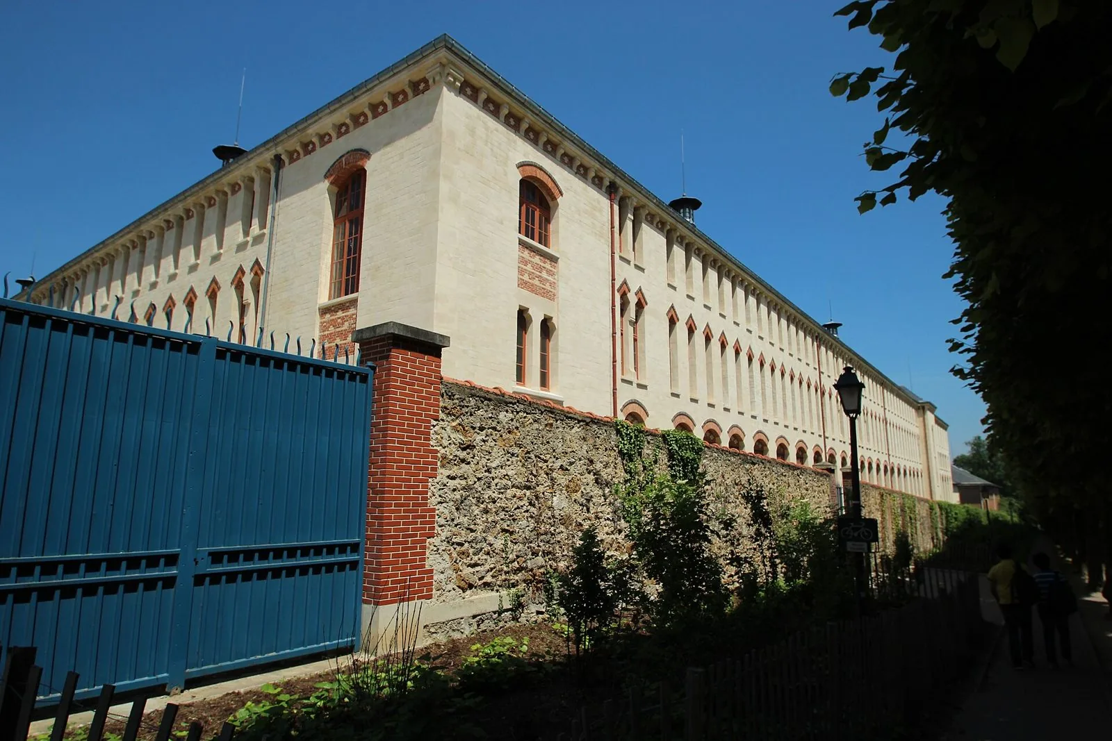 Facciata in pietra chiara e mattoni del Lycée Lakanal a Sceaux vista dal viale alberato